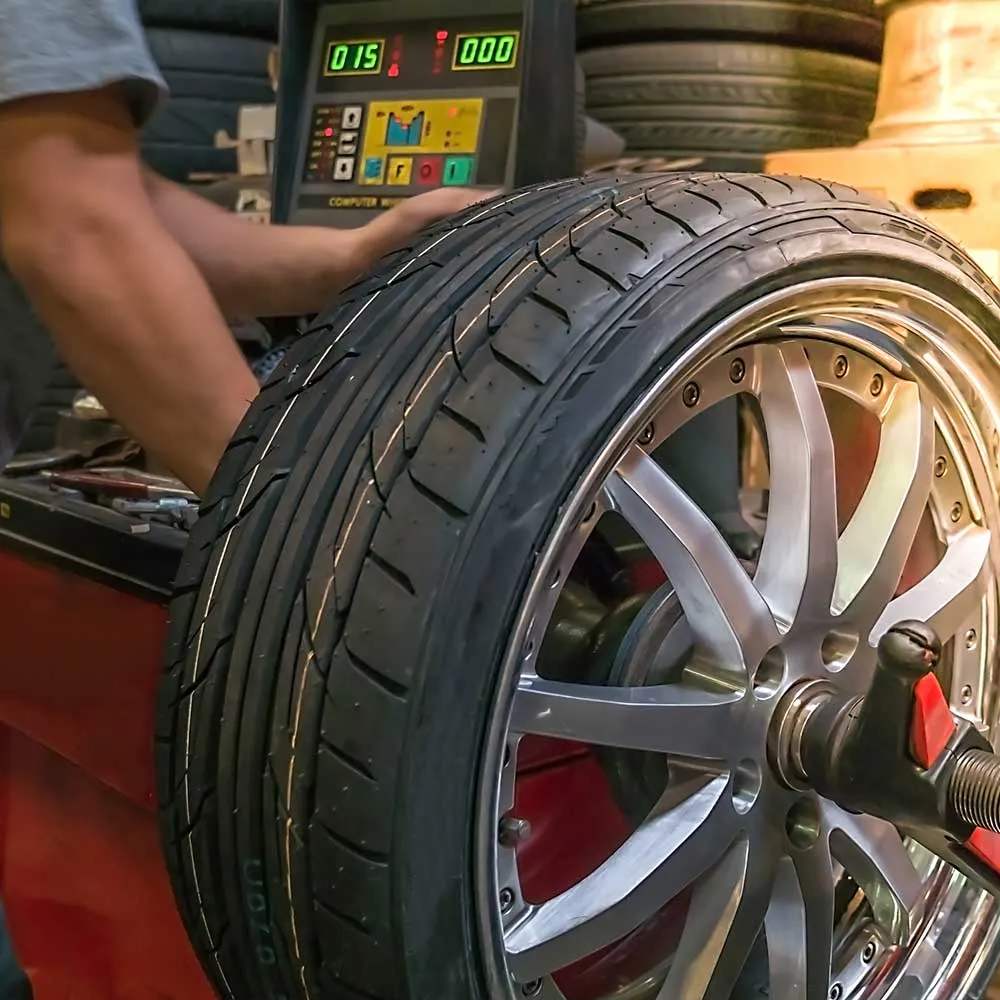 Mechanic balancing car tire in workshop